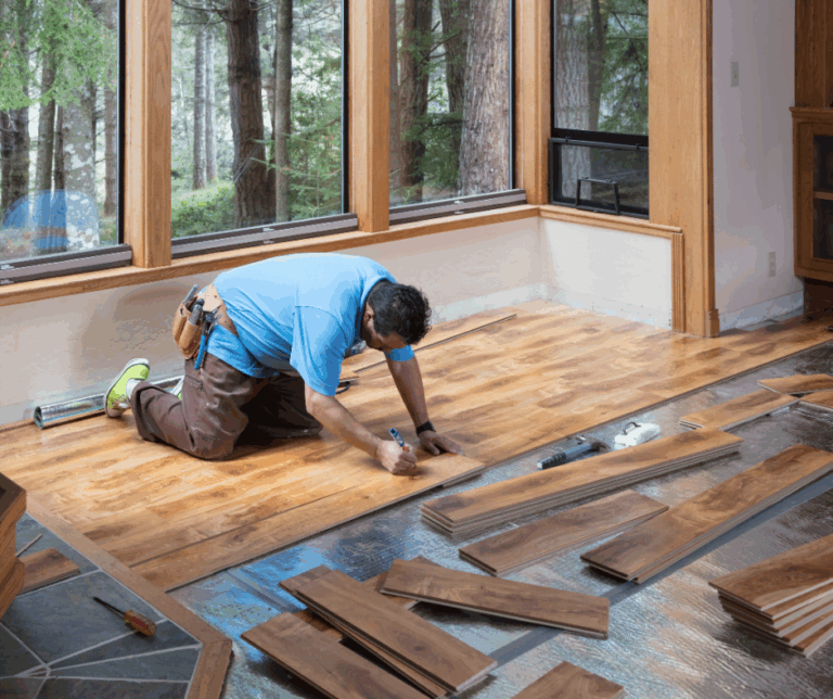 Person installing hardwood flooring in a bright room